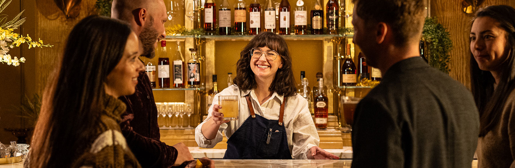 A Klocke Estate bartender offering up a just-finished cocktail to a group of happy people.